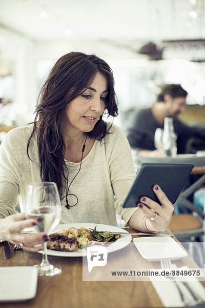 Frau mit digitalem Tablett im Restaurant