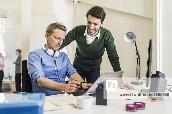 Businessmen discussing over laptop at desk in office