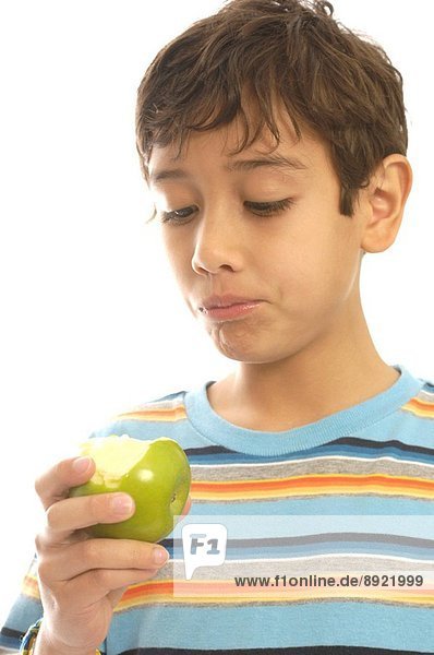 A young boy eating an apple and obviously not enjoying it.