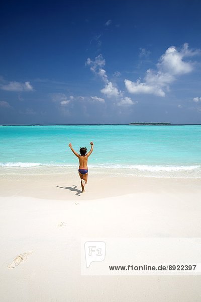 Boy running with arms raised on tropical beach  Maldives  Indian Ocean  Asia