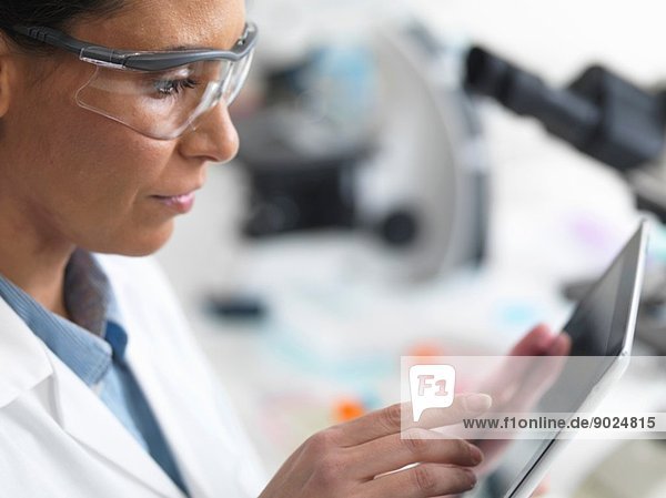 Wissenschaftlerin beim Betrachten der Testergebnisse auf einem digitalen Tablett im Labor