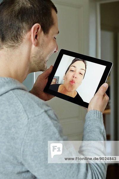 Mittlerer Erwachsener Mann  der mit dem Bildschirm eines digitalen Tabletts interagiert