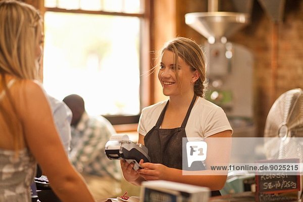Junge Frau serviert Kunden im Coffee-Shop