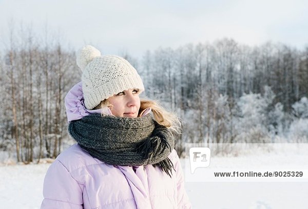 Mittlere erwachsene Frau in Winterkleidung im schneebedeckten Feld