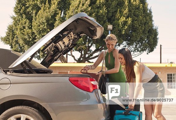 Junge Frauen stellen Koffer ins Auto