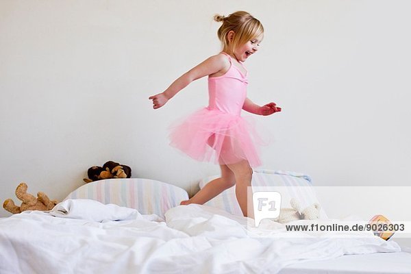 Mädchen verkleidet als Balletttänzerin auf dem Bett laufend