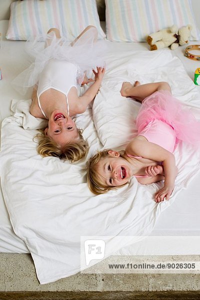 Porträt von zwei jungen Schwestern  die auf dem Bett spielen