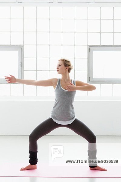 Junge Frau in Yoga-Pose stehend