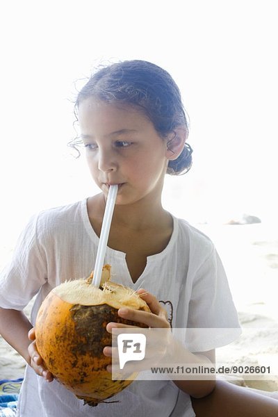 Mädchen trinkt aus einer Kokosnuss