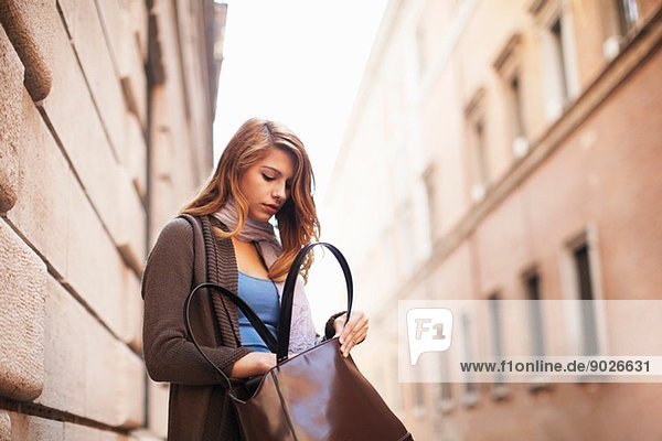 Young woman anxiously searching her shoulder bag