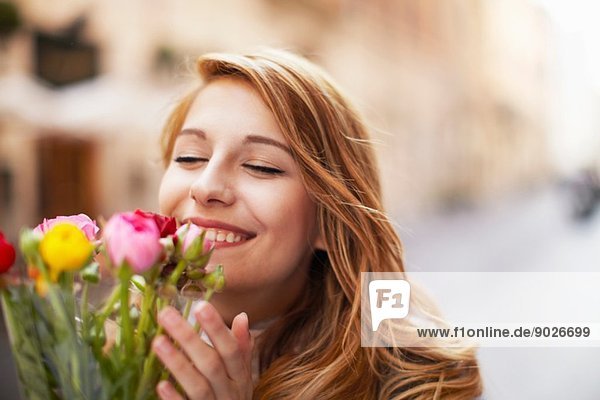 Lächelnde junge Frau  die einen Strauß Blumen riecht.