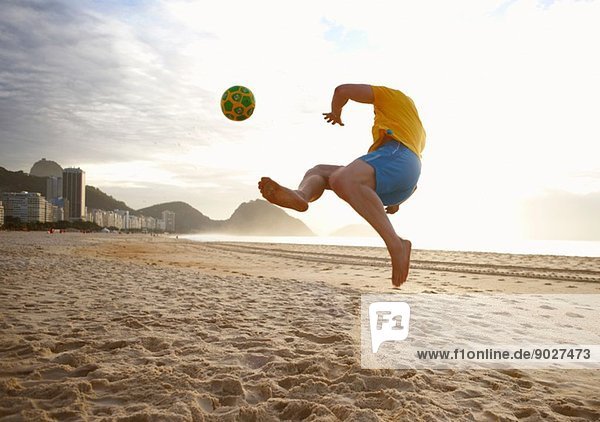 Ein erwachsener Mann spielt Fußball am Strand von Copacabana  Rio De Janeiro  Brasilien.