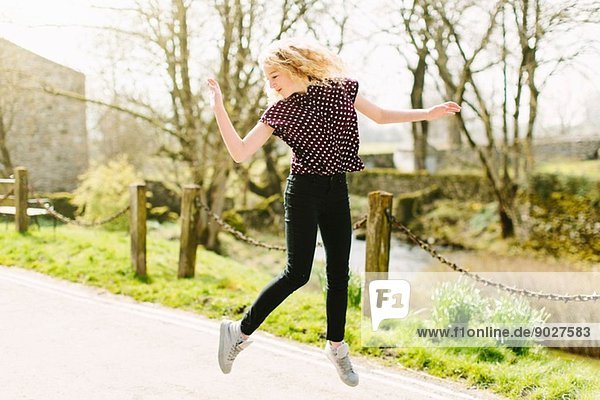 Teenager-Mädchen springt in der Luft auf dem Landweg