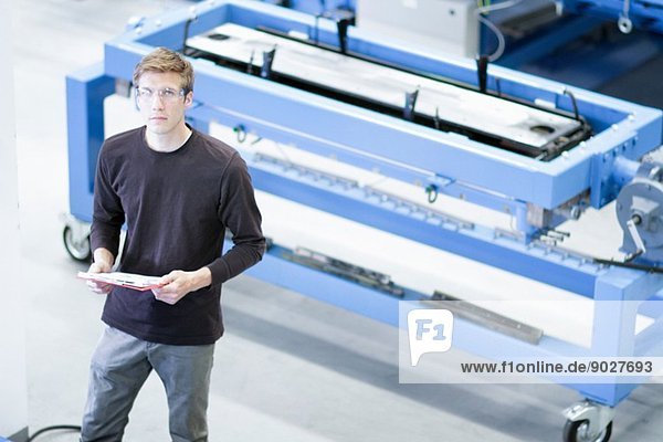 Porträt eines mittelgroßen Mannes mit Papierkram im Maschinenbaubetrieb