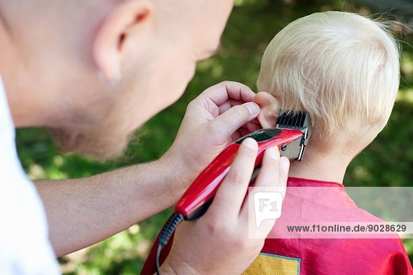 Vater schneidet Kleinkind Söhne Haare mit Schere