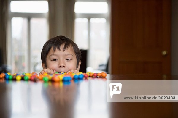 Boy peering over table at candy