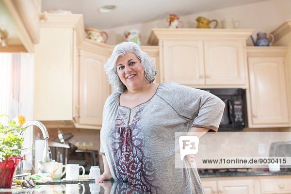 Porträt einer reifen Frau mit Hand auf der Hüfte in der Küche