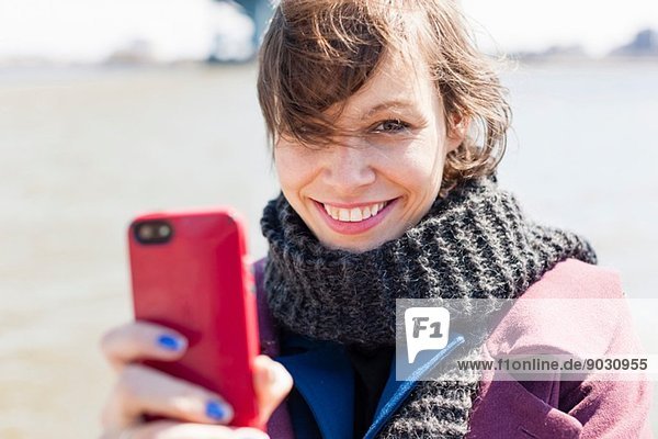 Close up portrait of young woman with smartphone