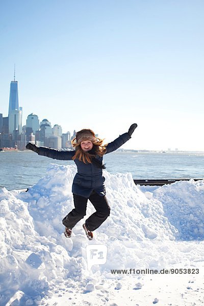 Mid adult woman jumping in snow  Manhattan  New York City  USA