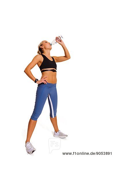 Young woman in sports clothes drinking water  studio shot