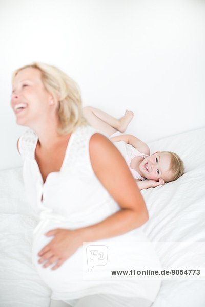 Happy mother with daughter on bed  studio shot