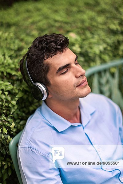 Young man with headphones on park bench  Bangkok  Thailand