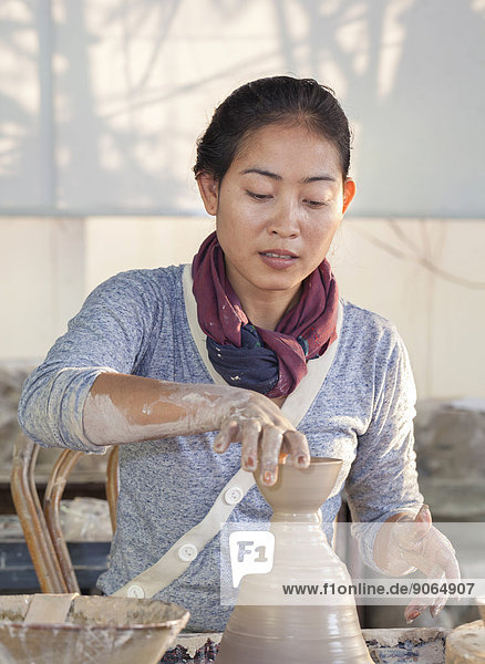 Frau formt Töpferware auf einer Töpferscheibe  Kambodscha