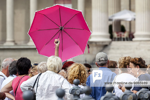 Touristengruppe mit einer Touristenführerin mit pinkfarbenem Regenschirm Budapest Ungarn