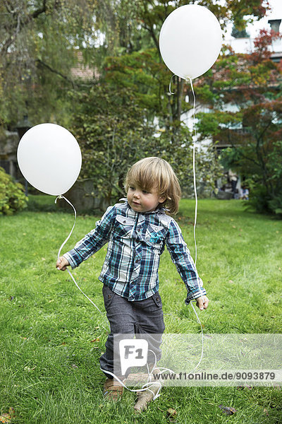 Kleinkind mit Ballons im Garten