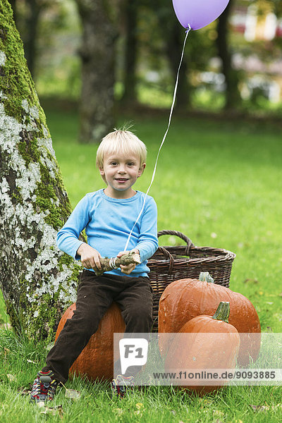 Junge mit Ballon und Kürbissen im Garten
