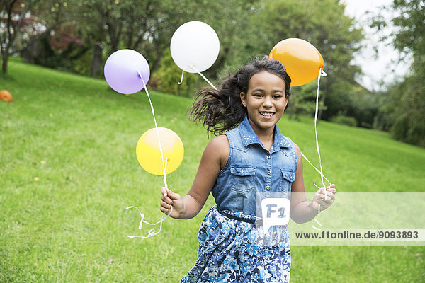Lächelndes Mädchen mit Luftballons im Garten