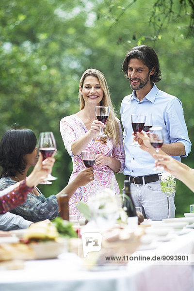 Couple holding glasses of red wine on a garden party