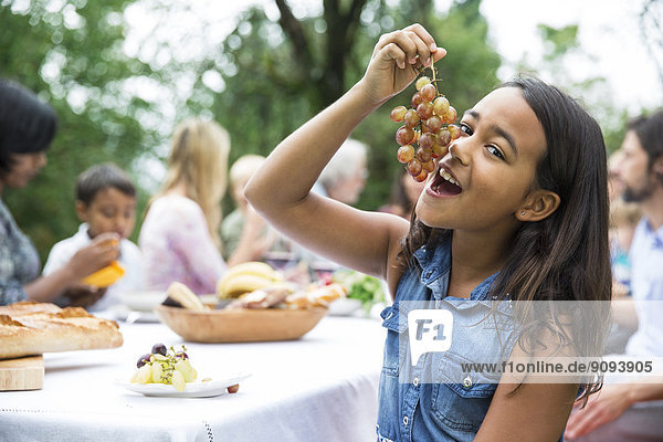 Mädchen beim Traubenessen auf einer Gartenparty