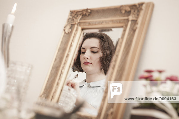 Junge Frau reflektiert im Spiegel auf einer Teeparty im Retro-Stil