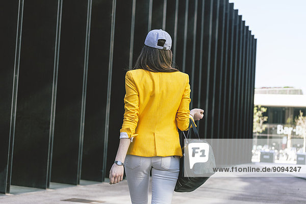 Spanien Catalunya  Barcelona  junge moderne Frau mit gelber Jacke unterwegs  Blick von hinten