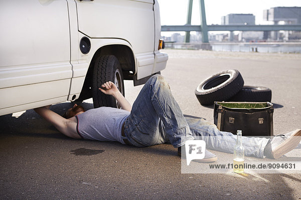 Mann auf dem Boden liegend  Auto reparierend