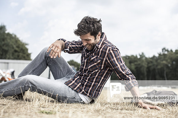 Lächelnder Mann auf Gras sitzend