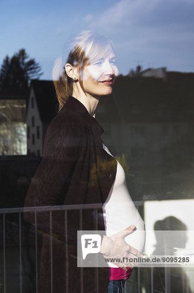 Schwangere Frau  die aus dem Fenster schaut