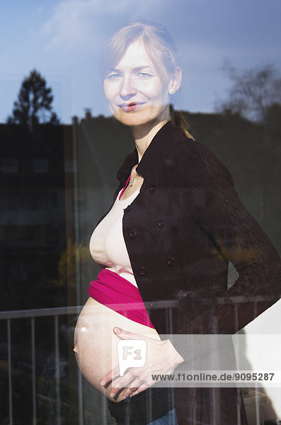 Schwangere Frau  die aus dem Fenster schaut