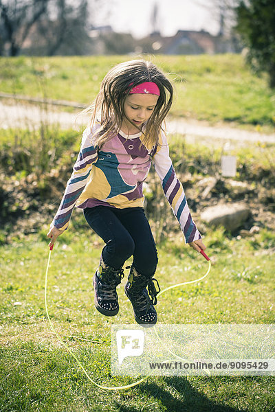 Kleines Mädchen springt Seil im Garten