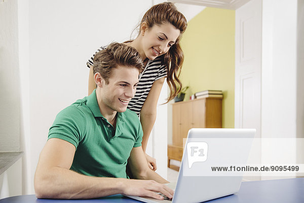 Young couple using laptop at home