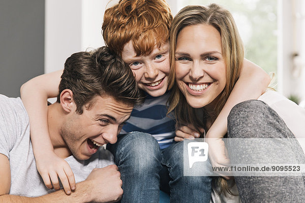 Porträt einer glücklichen jungen Familie  die auf der Couch im Wohnzimmer sitzt.