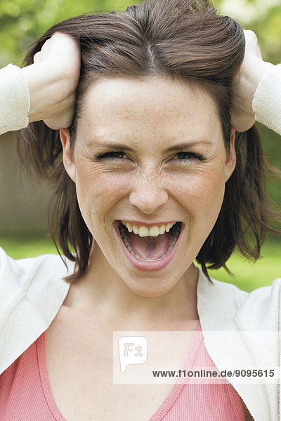 Portrait of screaming young woman with hands in her hair