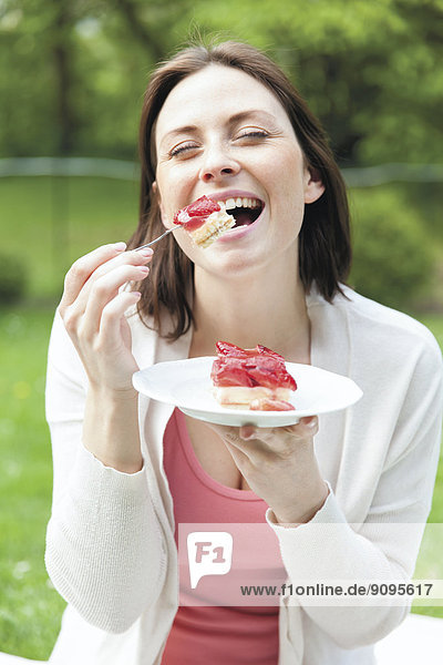 Porträt einer jungen Frau  die gerne Erdbeerkuchen isst