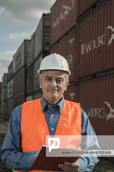 Mann mit Klemmbrett mit reflektierender Weste am Containerhafen
