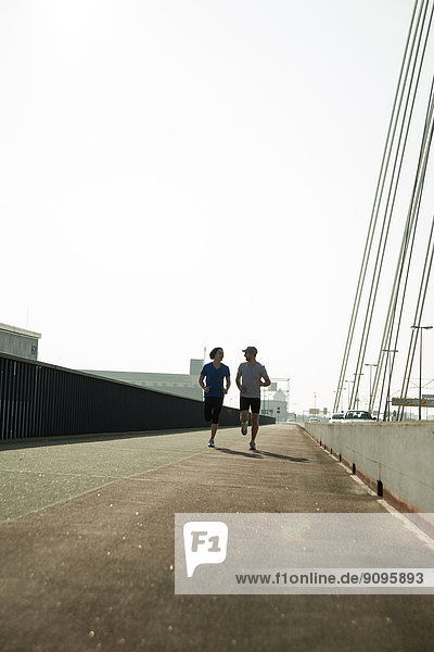 Junger Mann und Teenager laufen auf der Brücke