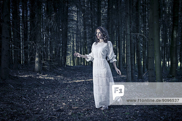 Frau in weißem Kleid im Wald