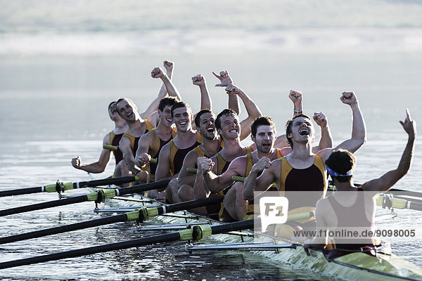 Rowing team celebrating in scull on lake