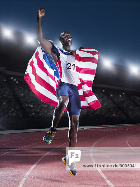 Läufer hält amerikanische Flagge und feiert auf der Strecke