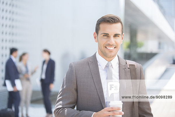 Porträt eines selbstbewussten Geschäftsmannes mit Kaffee im Freien